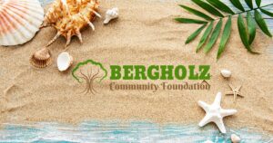 Sand with a collection of shells and the Bergholz Community Foundation logo