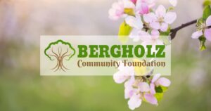 Pink flowers on a tree branch with the Bergholz Community Foundation logo overlayed in the middle of the image.